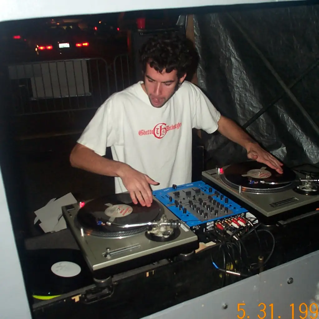 A DJ at a pair of turntables at a 2002 Burning Man decompression party.