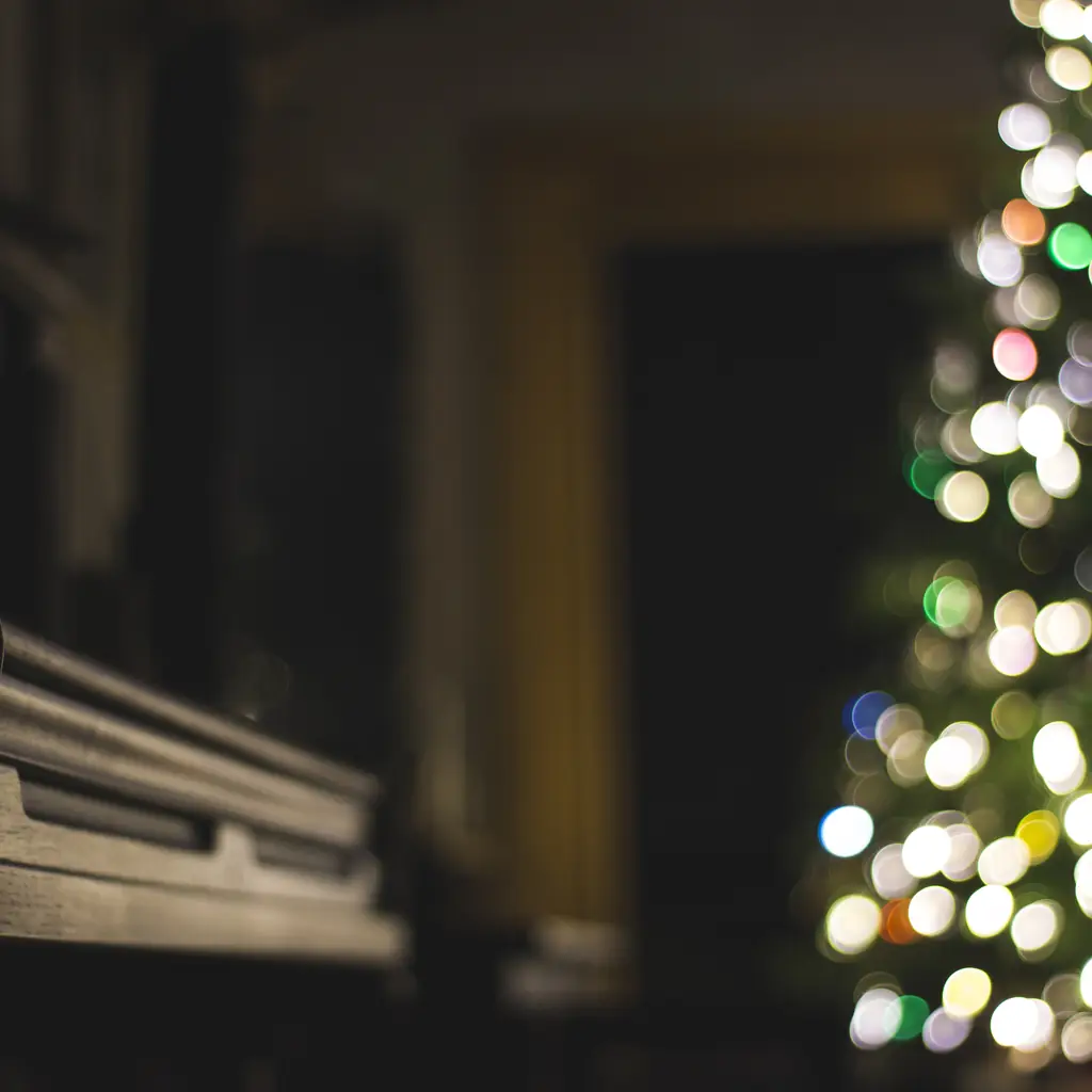 An upright piano with Christmas lights behind it.